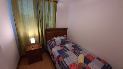 Un pequeño dormitorio con una cama y una lámpara en una mesa. en Vista Apartments - Aire Acondicionado y Estacionamiento, en Rancagua