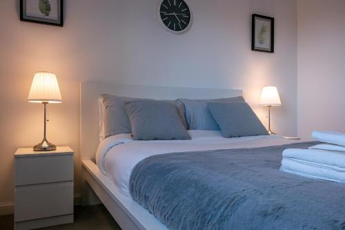 a bedroom with a large bed with a clock on the wall at Aryas Apartments Milton Keynes in Broughton