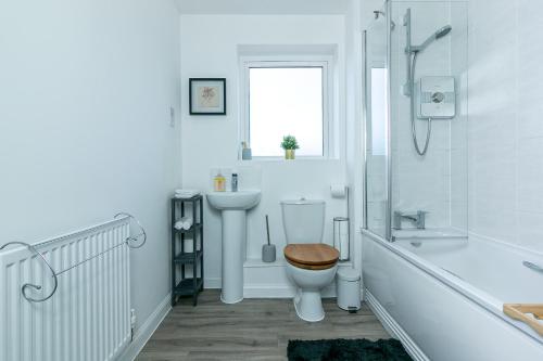 a white bathroom with a toilet and a sink at Aryas Apartments Milton Keynes in Broughton