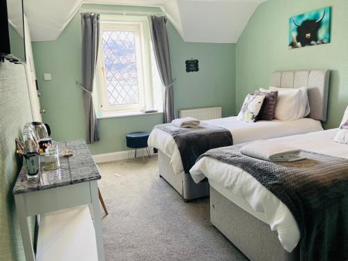 a small room with two beds and a window at Whinburn Guest House in Fort William