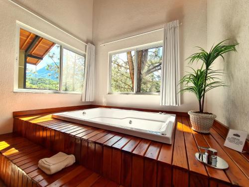 uma grande banheira num quarto com duas janelas em Pousada Serra da Índia em Penedo