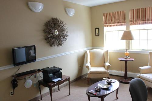 a living room with a tv and a couch and chairs at Garden South Park Inn in Halifax