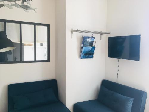 Cette chambre dispose de 2 chaises bleues et d'une télévision. dans l'établissement L' Appart du Marché, à La Rochelle