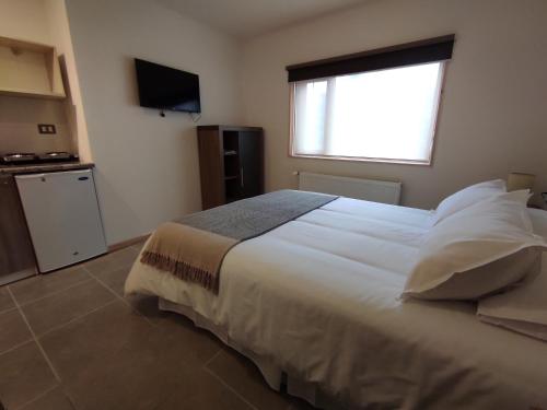 a bedroom with a large white bed with a window at Apart Hotel Endurance in Punta Arenas