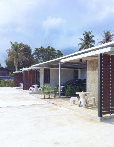 una fila de edificios con mesas y palmeras en LOFT Zone by โรงแรมพรรณ, en Ban Lahan Pa Phlu
