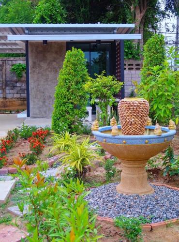 a garden with a large bird bath in a yard at LOFT Zone by โรงแรมพรรณ in Ban Lahan Pa Phlu