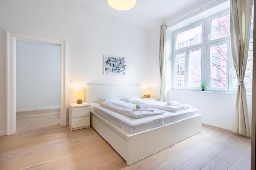 a white bedroom with a large bed and a window at Modernes Apartment im charmanten Cottage Viertel in Vienna