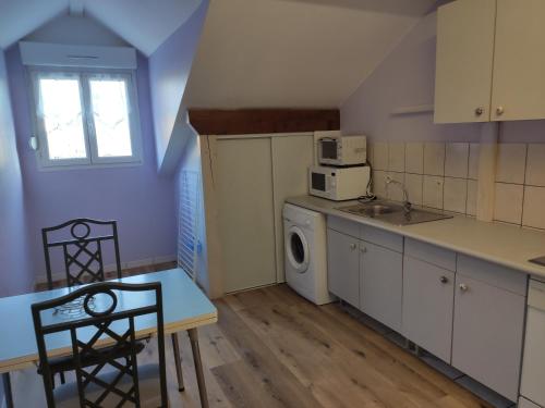a kitchen with a table and a sink and a washing machine at LES TILLEULS in Bains-les-Bains