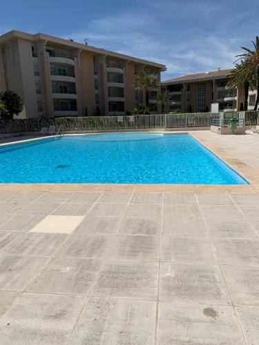 une grande piscine bleue devant un immeuble dans l'établissement Location Port Fréjus, bord de mer, à Fréjus