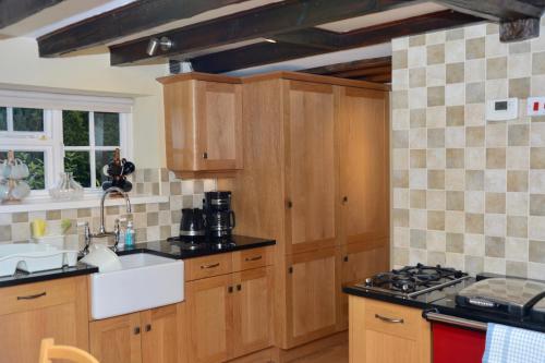 cocina con armarios de madera, fregadero y fogones en Forge Cottage, Helmsley, en Helmsley