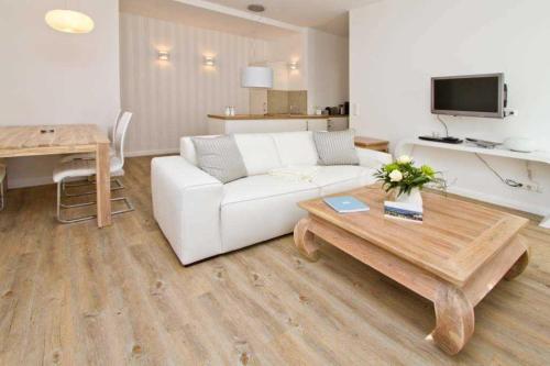 een woonkamer met een witte bank en een tafel bij Villa Waldschloss, App 01 in Heringsdorf