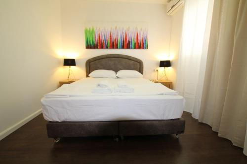a bedroom with a large white bed with two lamps at Isramax 3BR apartment near the sea. in Bat Yam