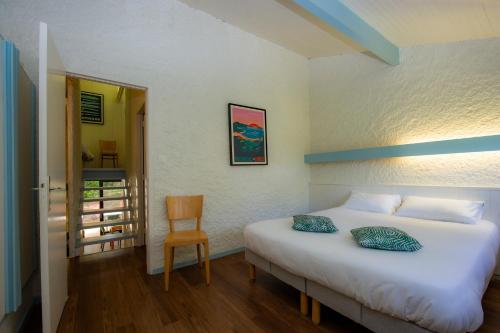 Un dormitorio con una cama blanca y una silla. en Résidence Vacances Bleues Domaine de l'Agréou, en Seignosse