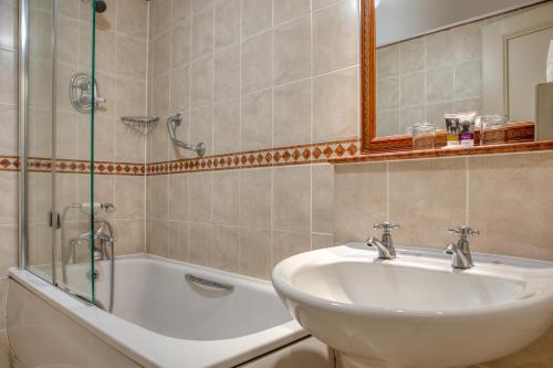 a bathroom with a sink and a bath tub at Winchester Wessex Hotel by Sunday in Winchester