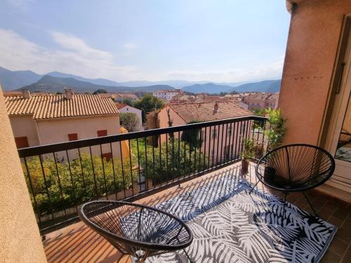 a balcony with two chairs and a view of a city at Bel appartement centre ville 3 chambres in Saint-Florent