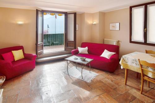 a living room with two red couches and a table at Appartamento Helvetia in Tremezzo