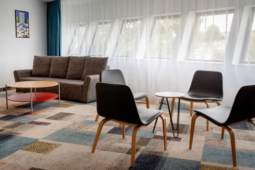 a living room with chairs and tables and a couch at Hotel Termalny in Uniejow