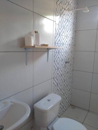 a white bathroom with a toilet and a sink at Chalé Pitanga in São Miguel do Gostoso