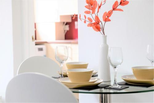 a table with glasses and a vase with flowers on it at Stunning 1 Bed at Holyrood Palace & Arthurs Seat in Edinburgh