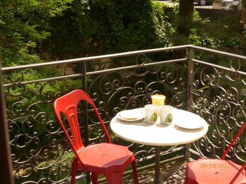 - une table avec deux chaises et deux tasses sur le balcon dans l'établissement Suite 22, à Aix-les-Bains