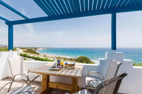 un tavolo e sedie su un balcone con vista sull'oceano di Anthos a Frangokastello