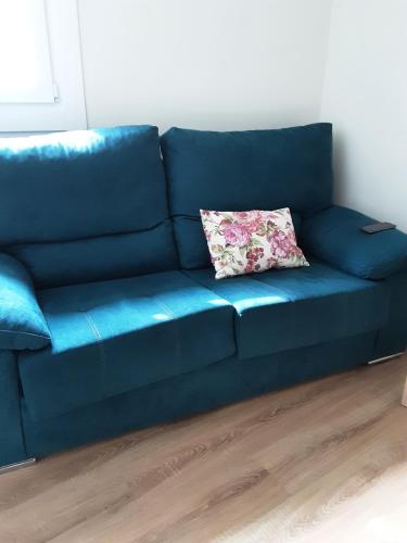 eine blaue Couch mit Kissen darauf in einem Zimmer in der Unterkunft Apartamentos Vetusta in Oviedo