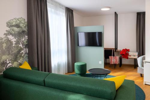 a living room with a green couch and a tv at Hôtel Du Dragon in Strasbourg
