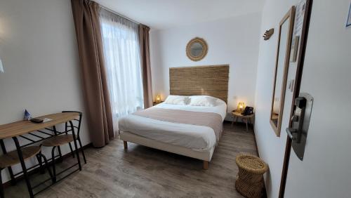 a bedroom with a bed and a table and a window at Le Relais du Valois Cognac Centre in Cognac