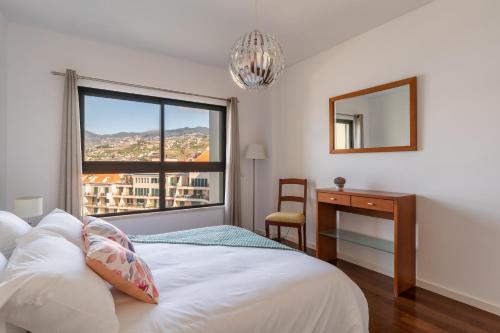 a bedroom with a bed and a desk and a window at Centromar Residence Ocean View By Atlantic Holiday in Funchal