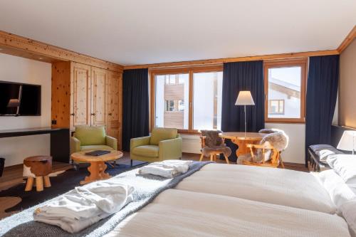 a bedroom with a large bed and a table and chairs at Boutique Hotel Cervus in St. Moritz
