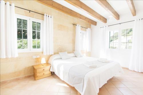 a white bedroom with a large bed with windows at Casa Maria by Sonne Villas in Ferreries
