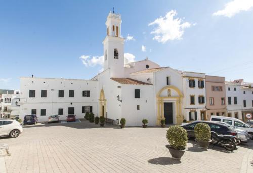 a large white church with a tower and cars parked at Casa Maria by Sonne Villas in Ferreries