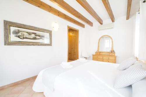 a white bedroom with a white bed and a mirror at Casa Maria by Sonne Villas in Ferreries