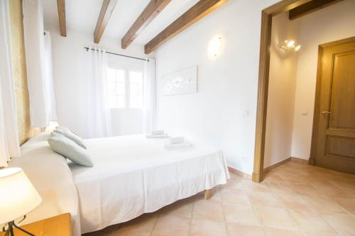 a bedroom with a white bed and a window at Casa Maria by Sonne Villas in Ferreries
