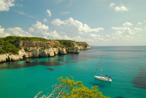 a boat in a body of water with cliffs at Casa Maria by Sonne Villas in Ferreries