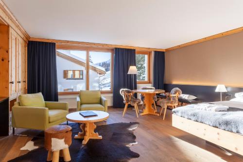 a bedroom with a bed and chairs and tables at Boutique Hotel Cervus in St. Moritz