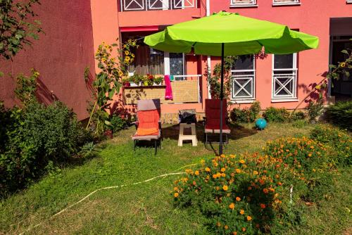 a green umbrella and chairs and flowers in front of a building at Sunny Day 6 - Menada Apartments in Sunny Beach