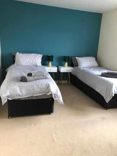 a bedroom with two beds and a blue wall at Bray House - Perfect for Large Groups in Wolverhampton