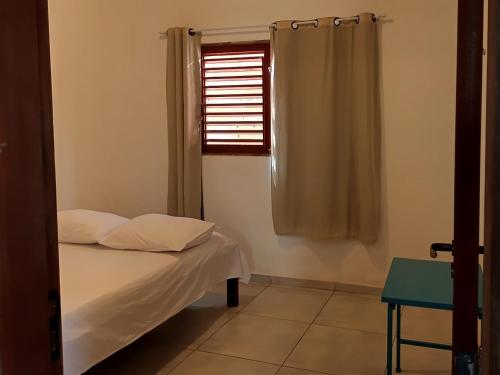 a small bedroom with a bed and a window at Chalé Pitanga in São Miguel do Gostoso