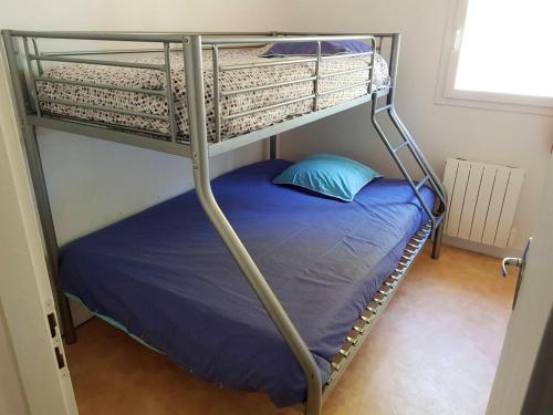 a bunk bed with a blue pillow on the bottom bunk at Maison confortable à Hourtin 33 m² avec terrasse in Hourtin