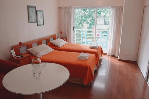 a bedroom with two beds and a table and a window at Palermo Deluxe Apartment in Buenos Aires