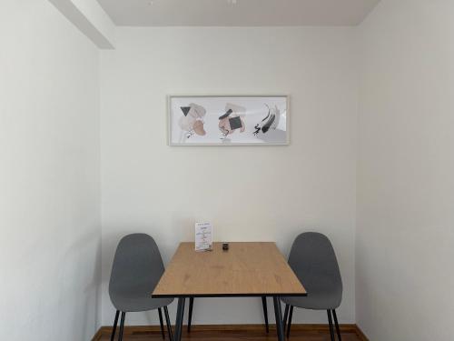 a table with three chairs and a picture on the wall at Moderne Studios im Herzen von Osnabrueck in Osnabrück