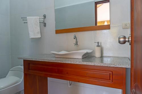 a bathroom with a sink and a toilet and a mirror at Hotel Coral Blanco with high speed internet Starlink in Puerto Villamil