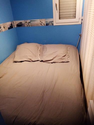un lit dans une chambre avec un mur bleu dans l'établissement Appartement confortable à Houlgate de 25 m² avec jardin, à Houlgate