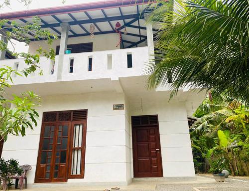 a white house with two doors and a balcony at Nilupul Villa in Ambalangoda