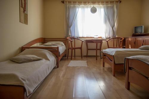 Habitación con 3 camas, mesa y ventana en The Zen Hostel - Posticum, en Oradea