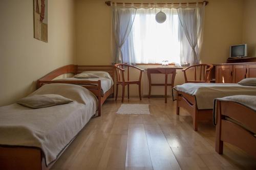 Zimmer mit 3 Betten, einem Tisch und einem Fenster in der Unterkunft The Zen Hostel - Posticum in Oradea