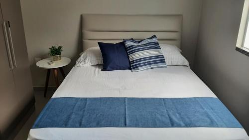 a bed with blue and white pillows in a bedroom at Apartamento encantador com estacionamento incluso em Tijucas in Tijucas