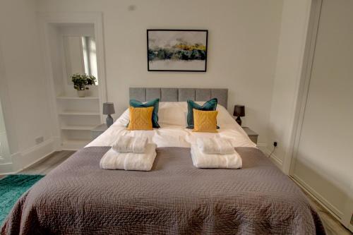 a bedroom with a large bed with pillows at Bright and stylish one bedroom apartment in Dundee