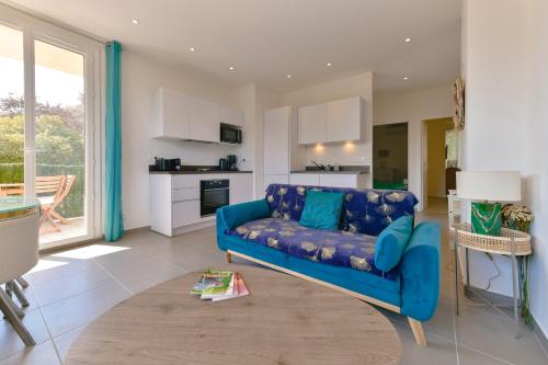 un salon avec un canapé bleu et une cuisine dans l'établissement Appartement refait à neuf, proche plage et centre ville- Ajaccio-Parc Berthaut, à Ajaccio
